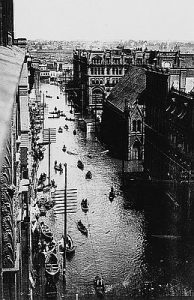 Photo of flooded downtown Portland street with people traveling via boat in June 1894