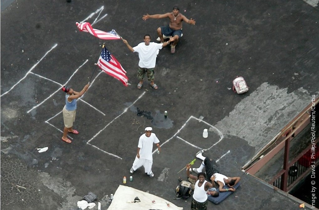 Photo of New Orleans residents signaling for help from their rooftop as floodwaters rise in 2005