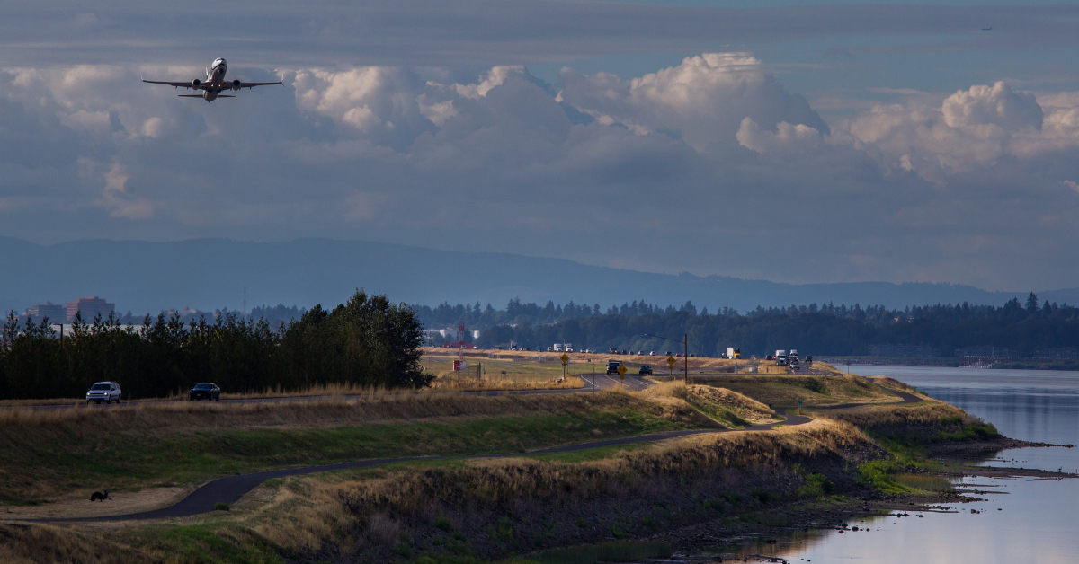 Photo of Marine Drive levee along the Columbia River with airplane taking off from the Portland International Airport behind the levee
